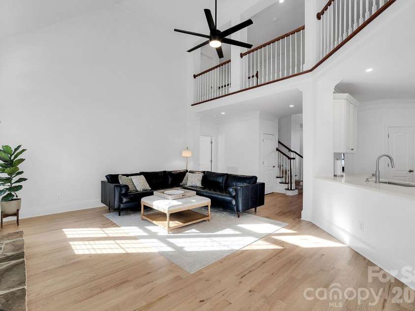 7778 Burning Ridge Drive, Stanley, NC 28164.  MLS# CAR4336313, YatesRealty ID 13726. Dramatic living room with soaring ceilings, fireplace focal point, and expansive windows. The open design creates a bright and airy atmosphere.
