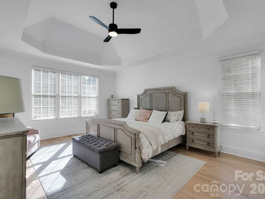 7778 Burning Ridge Drive, Stanley, NC 28164.  MLS# CAR4336313, YatesRealty ID 13726. Spacious primary bedroom featuring a tray ceiling, ceiling fan, and abundant natural light. Soft finishes and generous layout create a comfortable retreat.