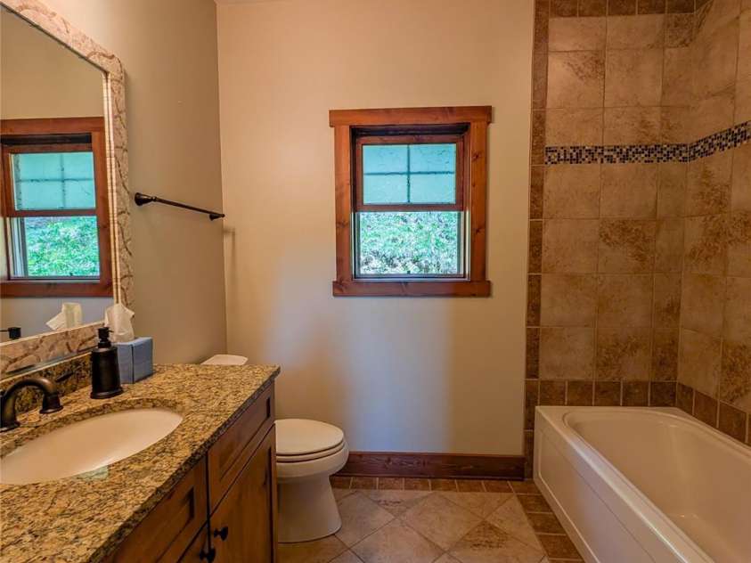 13 Miners Trace Road, Burnsville, NC 28714.  MLS# CAR4206928, YatesRealty ID 13994. Guest Bathroom at end of hallway offers granite countertop, tile flooring and tile shower with tub.