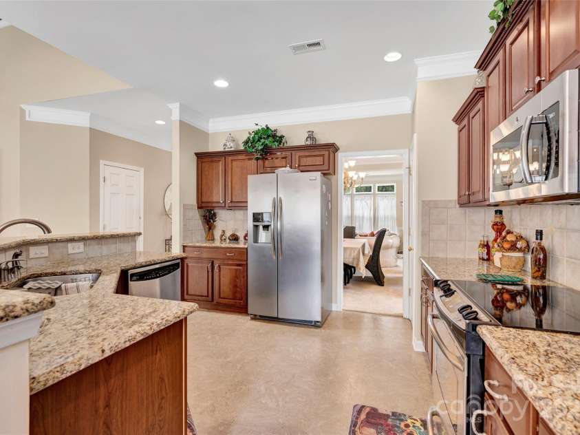 141 Ivy Creek Lane, Mooresville, NC 28115.  MLS# CAR4246190, YatesRealty ID 14012. Another view of the kitchen with granite tops, flattop range, tile backsplash and microwave.