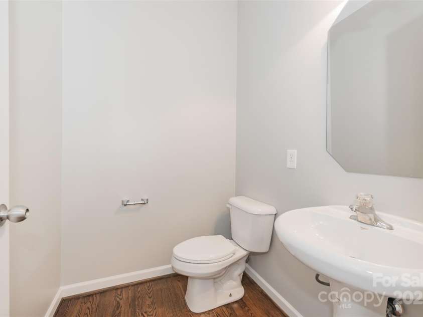 10008 King George Lane, Waxhaw, NC 28173.  MLS# CAR4257017, YatesRealty ID 14025. This tastefully appointed powder room, with rich hardwood floors and a sleek pedestal sink, is privately situated for ultimate convenience—because sometimes, you just need a stylish escape that doesn’t involve anyone a