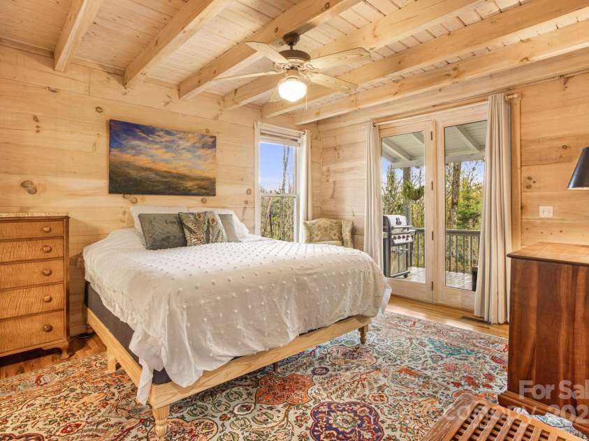 60 Laurel Lane, Mars Hill, NC 28754.  MLS# CAR4256396, YatesRealty ID 14054. Main level primary bedroom with doors leading out onto the covered back deck.