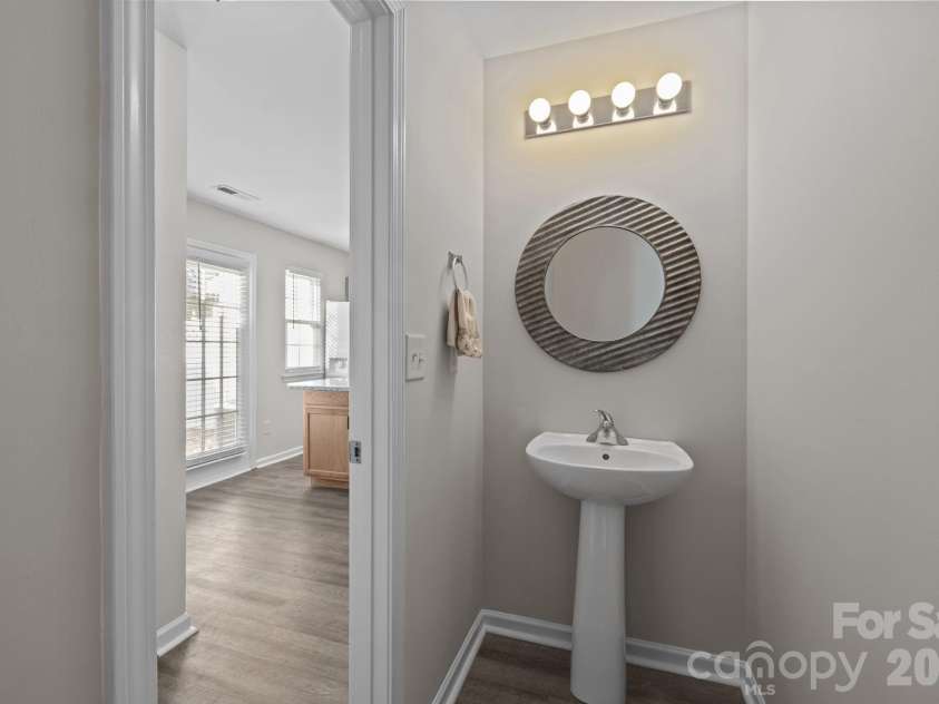 209 Primrose Walk, Fort Mill, SC 29715.  MLS# CAR4346413, YatesRealty ID 14281. Half bath behind the kitchen with decorative mirror and pedestal sink.