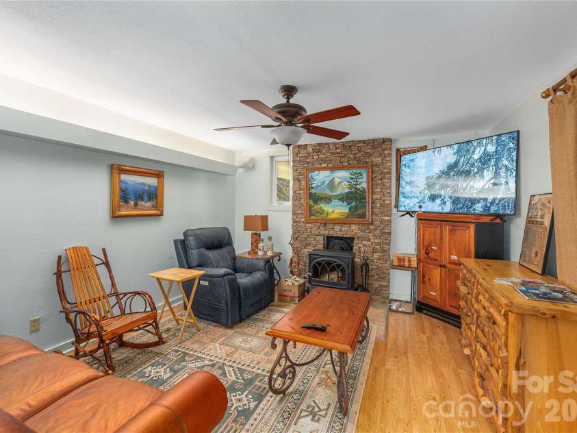12 Bear Cove Lane, Bryson City, NC 28713.  MLS# CAR4337192, YatesRealty ID 1456. Open living room with stone hearth and wall and wood stove