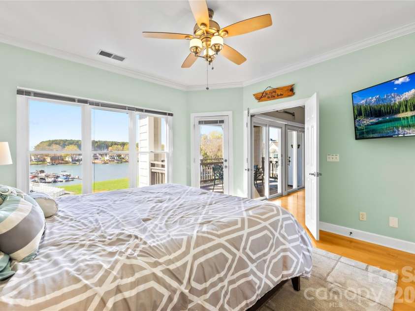 18700 Nautical Drive, Cornelius, NC 28031.  MLS# CAR4357308, YatesRealty ID 14763. Primary Bedroom with lake views, hardwoods floors and flat screen TV on wall will remain.