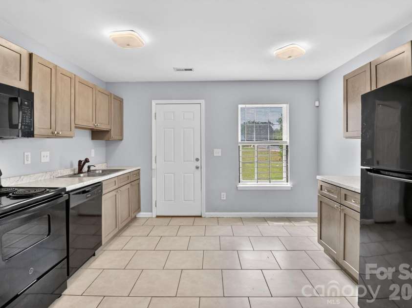 3335 Avalon Avenue, Charlotte, NC 28208.  MLS# CAR4373302, YatesRealty ID 14902. Efficient & Bright KitchenStyle: Warm wood-toned Shaker cabinets paired with sleek black GE appliances.Countertops: Light marble-patterned counters with a double stainless sink.Flooring: Easy-to-clean neutral tile throu