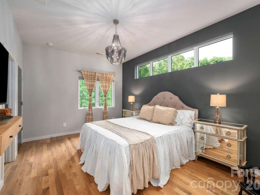 559 Shining Rock Path, Horse Shoe, NC 28742.  MLS# CAR4372540, YatesRealty ID 14910. Spacious primary suite with bold accent wall, clerestory windows, and serene treetop views.