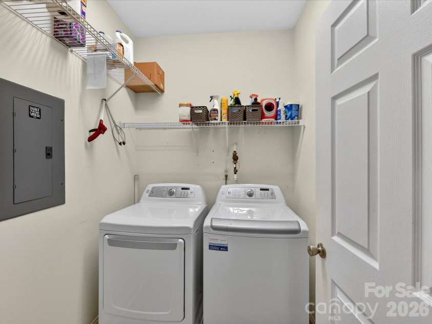 8665 Edinburgh Square Drive, Cornelius, NC 28031.  MLS# CAR4357240, YatesRealty ID 15038. Convenient laundry room featuring a full-size washer and dryer with built-in shelving for added storage and organization.