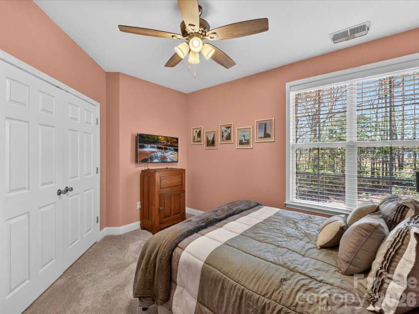 8665 Edinburgh Square Drive, Cornelius, NC 28031.  MLS# CAR4357240, YatesRealty ID 15038. Cozy third bedroom featuring soft carpeting, a ceiling fan, and abundant natural light, perfect for guests or additional living space.