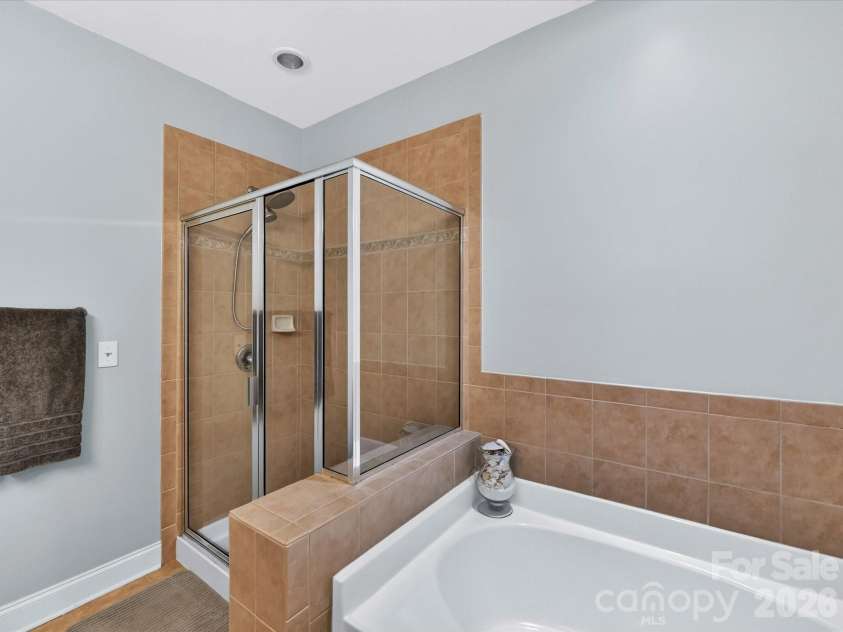 8665 Edinburgh Square Drive, Cornelius, NC 28031.  MLS# CAR4357240, YatesRealty ID 15038. Spacious primary bath featuring a double vanity, large mirror, and separate glass-enclosed shower for a comfortable and functional layout.