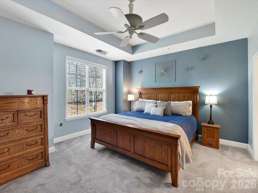 8665 Edinburgh Square Drive, Cornelius, NC 28031.  MLS# CAR4357240, YatesRealty ID 15038. Spacious primary suite featuring tray ceilings, abundant natural light, plush carpeting, and a serene, airy atmosphere perfect for relaxing.