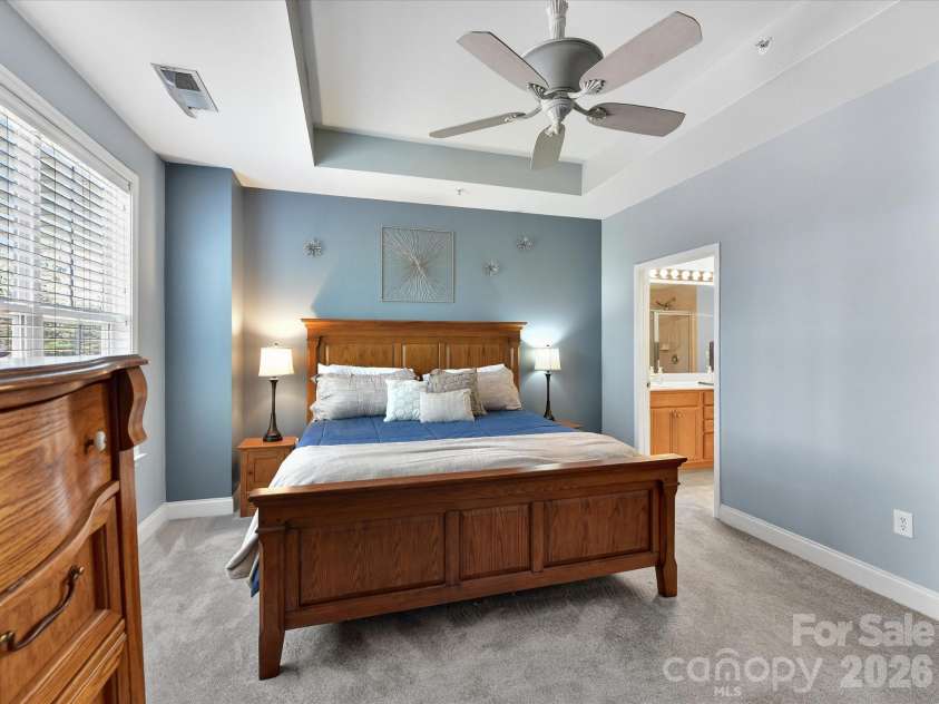 8665 Edinburgh Square Drive, Cornelius, NC 28031.  MLS# CAR4357240, YatesRealty ID 15038. Spacious primary suite featuring tray ceilings, abundant natural light, plush carpeting, and a serene, airy atmosphere perfect for relaxing.