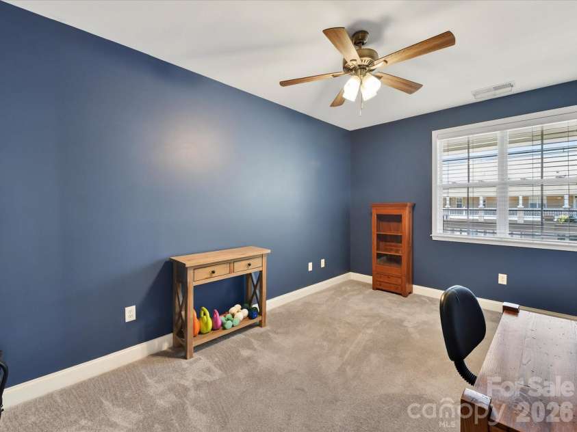 8665 Edinburgh Square Drive, Cornelius, NC 28031.  MLS# CAR4357240, YatesRealty ID 15038. Versatile second bedroom featuring plush carpeting, abundant natural light, and ample space ideal for guests, a home office, or flex use.