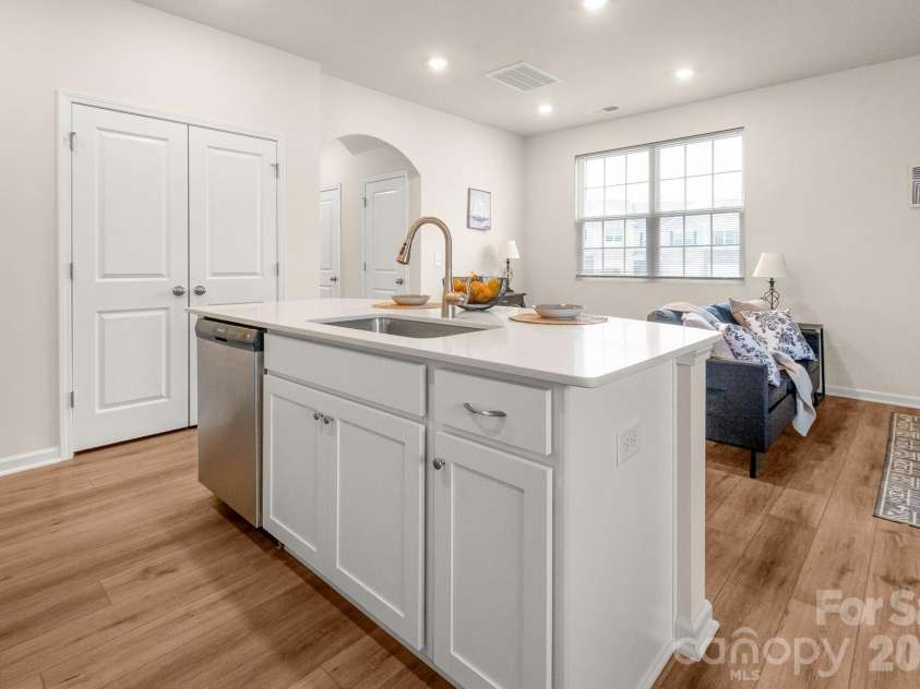 5044 Moss Pine Way, Tega Cay, SC 29708.  MLS# CAR4371971, YatesRealty ID 15096. Another angle reveals the full kitchen — double pantry doors, gas range, and a large island with undermount sink. Every detail has been considered.