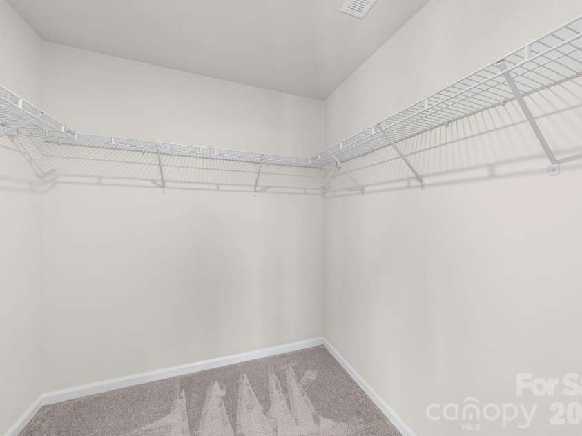 5044 Moss Pine Way, Tega Cay, SC 29708.  MLS# CAR4371971, YatesRealty ID 15096. Generous walk-in closet off the primary suite with built-in shelving on three walls — plenty of space to stay organized and keep everything within reach.