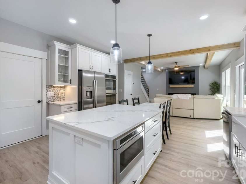 28838 Hwy 73 Highway, Albemarle, NC 28001.  MLS# CAR4373595, YatesRealty ID 15144. Full kitchen perspective featuring the oversized island with quartz waterfall extension, double ovens, glass-front cabinetry, and pendant lighting — designed to impress.