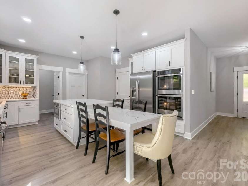 28838 Hwy 73 Highway, Albemarle, NC 28001.  MLS# CAR4373595, YatesRealty ID 15144. Island-centered view showcasing the built-in microwave drawer, stainless refrigerator, double wall ovens, and open sightlines to the great room and deck.