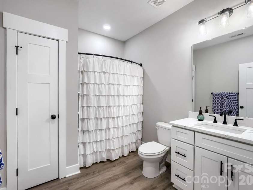 28838 Hwy 73 Highway, Albemarle, NC 28001.  MLS# CAR4373595, YatesRealty ID 15144. Secondary full bath featuring white shaker vanity, quartz countertop, black hardware accents, farmhouse lighting, and LVP flooring.