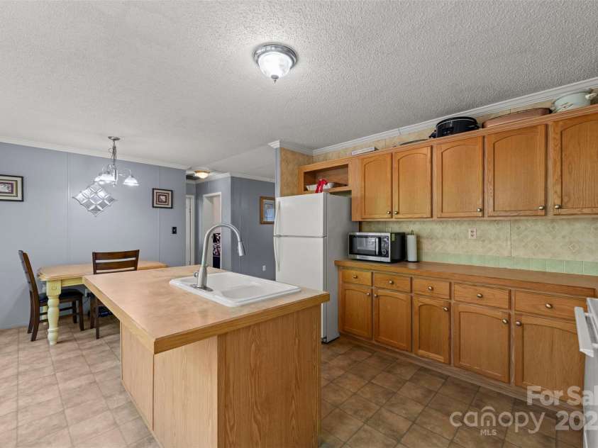 5039 Pine Springs Drive, Bessemer City, NC 28016.  MLS# CAR4249727, YatesRealty ID 15175. Kitchen with Island Bar area and showing off the tremendous amounts of cabinets and counter space and the eat in dining area.  Sink and dishwasher is in the kitchen island