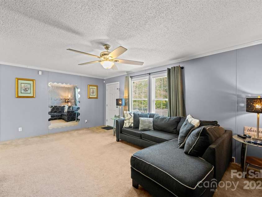 5039 Pine Springs Drive, Bessemer City, NC 28016.  MLS# CAR4249727, YatesRealty ID 15175. Living room view from the primary bedroom looking out through the windows to the front deck