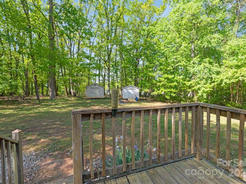 5039 Pine Springs Drive, Bessemer City, NC 28016.  MLS# CAR4249727, YatesRealty ID 15175. View from the back door looking into the back yard featuring the 2 storage sheds.  Check out all the back yard privacy