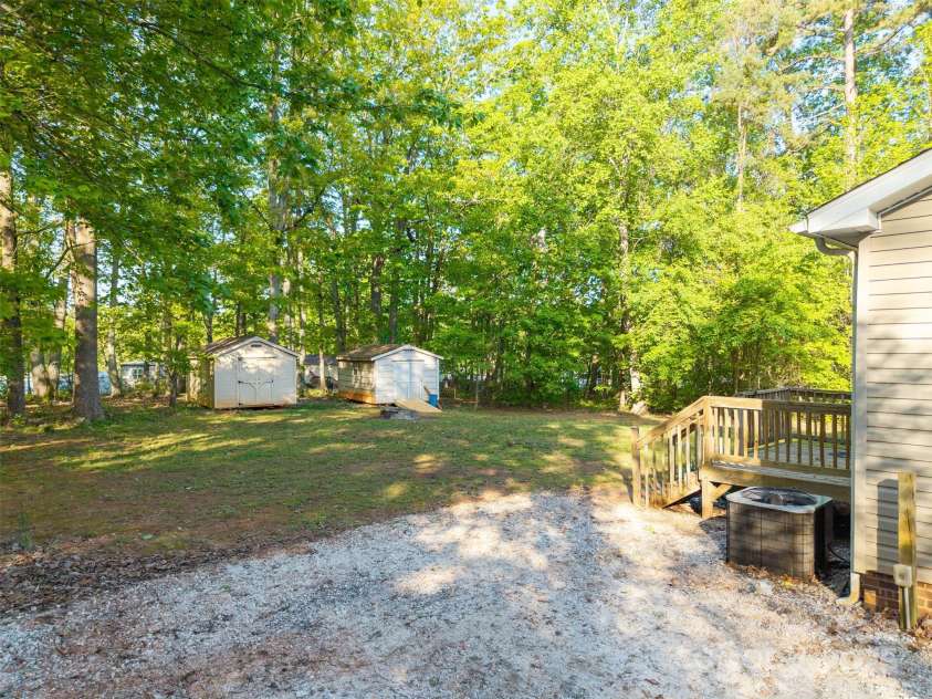 5039 Pine Springs Drive, Bessemer City, NC 28016.  MLS# CAR4249727, YatesRealty ID 15175. View of the two sheds and the stone fire pit in the back yard