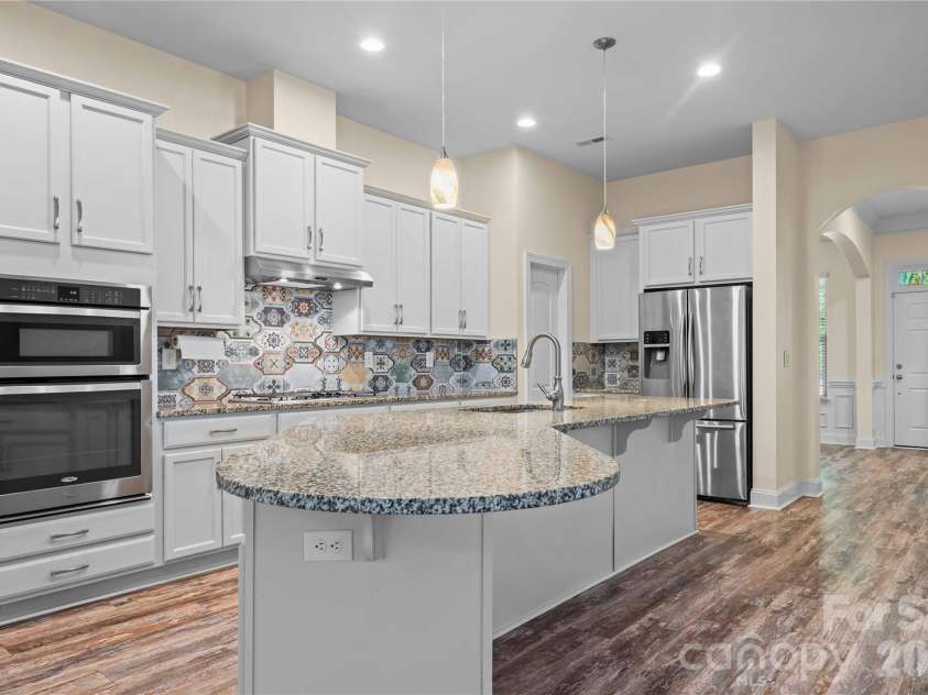 7017 Hyde Park Drive, Indian Trail, NC 28079.  MLS# CAR4369830, YatesRealty ID 15235. Chef's kitchen features gorgeous custom tile backsplash, large island, painted cabinets/drawers, gas cooktop, pendant lighting, stainless steel appliances, stainless steel double sink, walk-in pantry, and more!