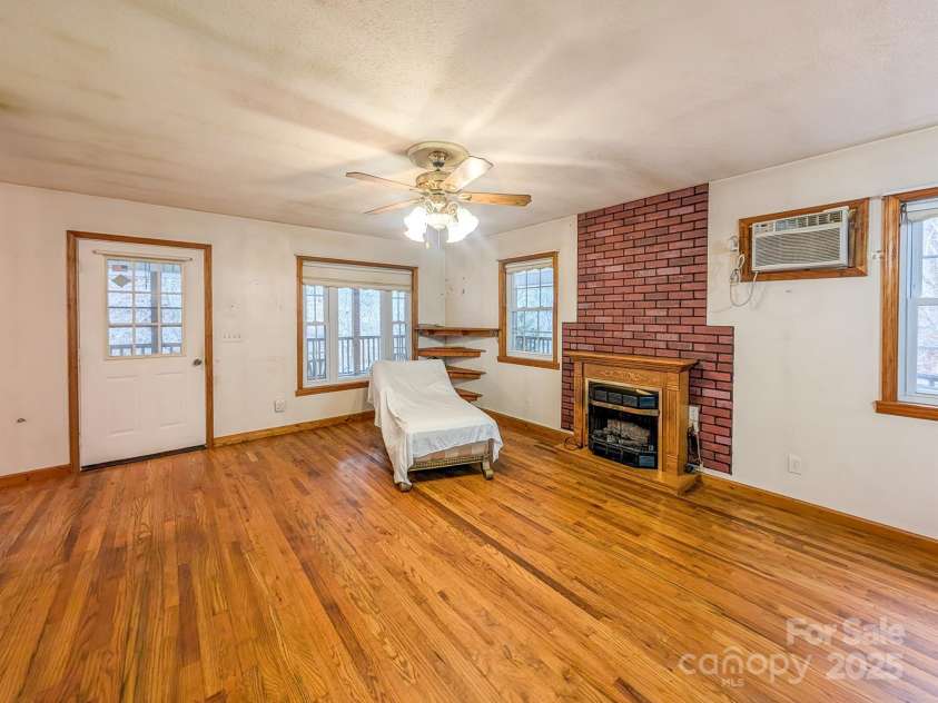 77 Griffith Branch Road, Green Mountain, NC 28740.  MLS# CAR4328405, YatesRealty ID 1531. Spacious living area features hardwood flooring, propane gas log fireplace and access to covered wrap-around porch. 