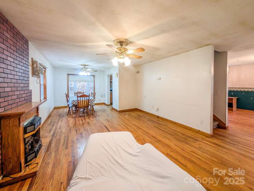 77 Griffith Branch Road, Green Mountain, NC 28740.  MLS# CAR4328405, YatesRealty ID 1531. Spacious living area features hardwood flooring, propane gas log fireplace and access to covered wrap-around porch. Could use space for small dining area as shown or additional room to right - den/flex space - 