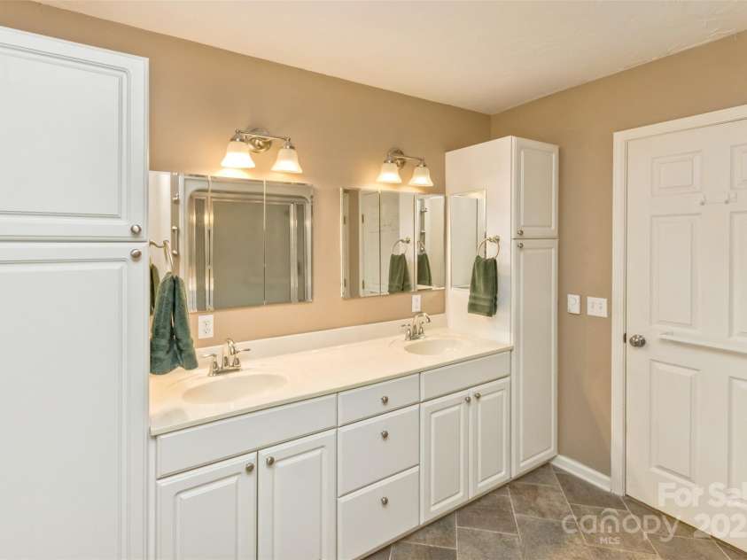 15 Beaverdam Knoll Road, Asheville, NC 28804.  MLS# CAR4283730, YatesRealty ID 1568. The primary bathroom is complete with a built-in double vanity, storage cabinets and a separate linen closet. 