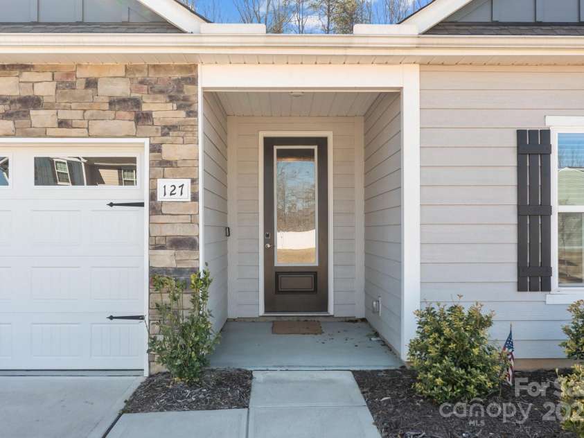 127 Tradesmen Trail, Troutman, NC 28166.  MLS# CAR4223474, YatesRealty ID 15779. The covered entry to the home features a welcoming front door equipped with an electronic key pad, offering both convenience and security. This thoughtful touch ensures easy access while adding a modern element to the h