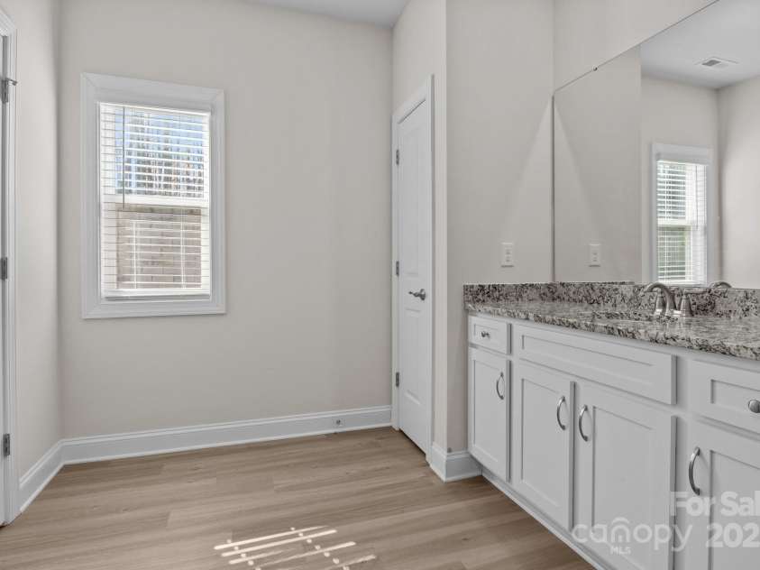 127 Tradesmen Trail, Troutman, NC 28166.  MLS# CAR4223474, YatesRealty ID 15779. The en-suite bathroom includes dual vanities, a large shower, and a linen closet for extra storage, all enhanced by natural light from a well-placed window, creating a bright and functional space.
