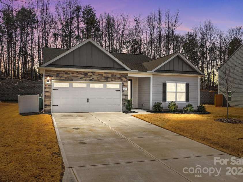 127 Tradesmen Trail, Troutman, NC 28166.  MLS# CAR4223474, YatesRealty ID 15779. The front of the home, captured at dusk, highlights the beautiful hardyboard siding and elegant stacked stone veneer, creating a timeless and durable exterior. The soft twilight glow accentuates the home's architectural