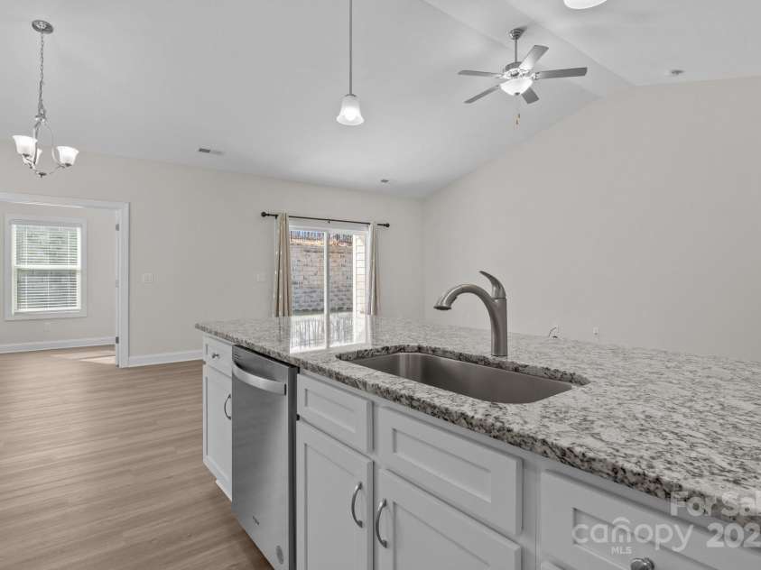 127 Tradesmen Trail, Troutman, NC 28166.  MLS# CAR4223474, YatesRealty ID 15779. The modern kitchen features a large island with granite countertops, a stainless steel sink, and a dishwasher, making meal prep and cleanup a breeze. With ample cabinetry and stainless steel appliances, the space is bot