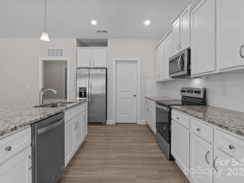 127 Tradesmen Trail, Troutman, NC 28166.  MLS# CAR4223474, YatesRealty ID 15779. The modern kitchen is designed for both functionality and style, featuring a large walk-in pantry conveniently located just off the kitchen, providing ample storage space. With granite countertops, stainless steel appli