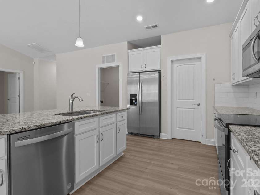 127 Tradesmen Trail, Troutman, NC 28166.  MLS# CAR4223474, YatesRealty ID 15779. The modern kitchen is designed for both functionality and style, featuring a large walk-in pantry conveniently located just off the kitchen, providing ample storage space. With granite countertops, stainless steel appli