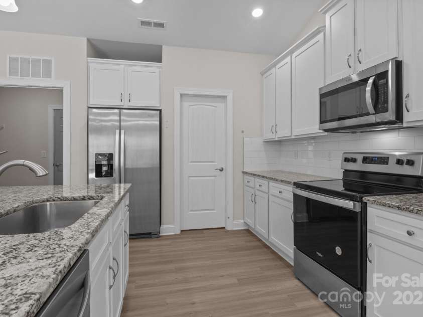 127 Tradesmen Trail, Troutman, NC 28166.  MLS# CAR4223474, YatesRealty ID 15779. The modern kitchen is designed for both functionality and style, featuring a large walk-in pantry conveniently located just off the kitchen, providing ample storage space. With granite countertops, stainless steel appli