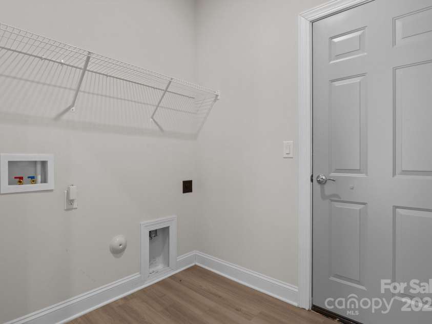 127 Tradesmen Trail, Troutman, NC 28166.  MLS# CAR4223474, YatesRealty ID 15779. The mud room, conveniently located between the garage and the kitchen, offers a practical space for storing shoes, coats, and everyday items. This multifunctional area also serves as the laundry room, featuring a shelf 