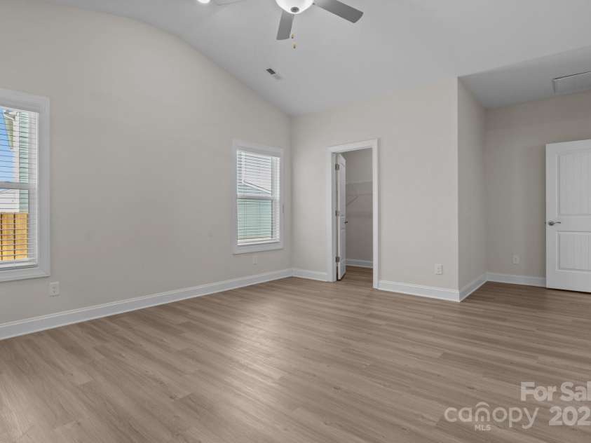 127 Tradesmen Trail, Troutman, NC 28166.  MLS# CAR4223474, YatesRealty ID 15779. The primary bedroom offers a serene retreat with generous space, abundant natural light, and stylish vinyl plank flooring. The en-suite bathroom features dual vanities and a spacious shower, creating a spa-like experien