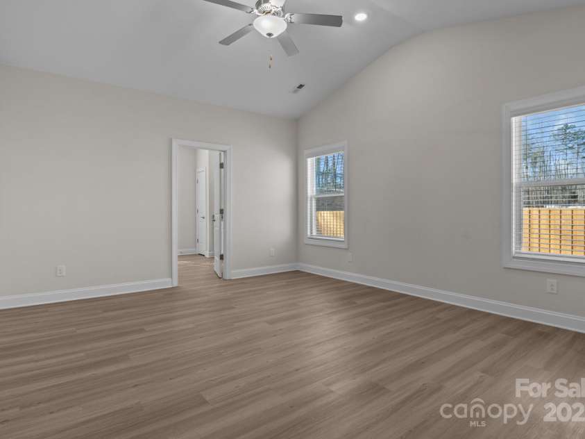 127 Tradesmen Trail, Troutman, NC 28166.  MLS# CAR4223474, YatesRealty ID 15779. The primary bedroom offers a serene retreat with generous space, abundant natural light, and stylish vinyl plank flooring. The vaulted ceiling enhances the open feel, while the ceiling fan provides added comfort.