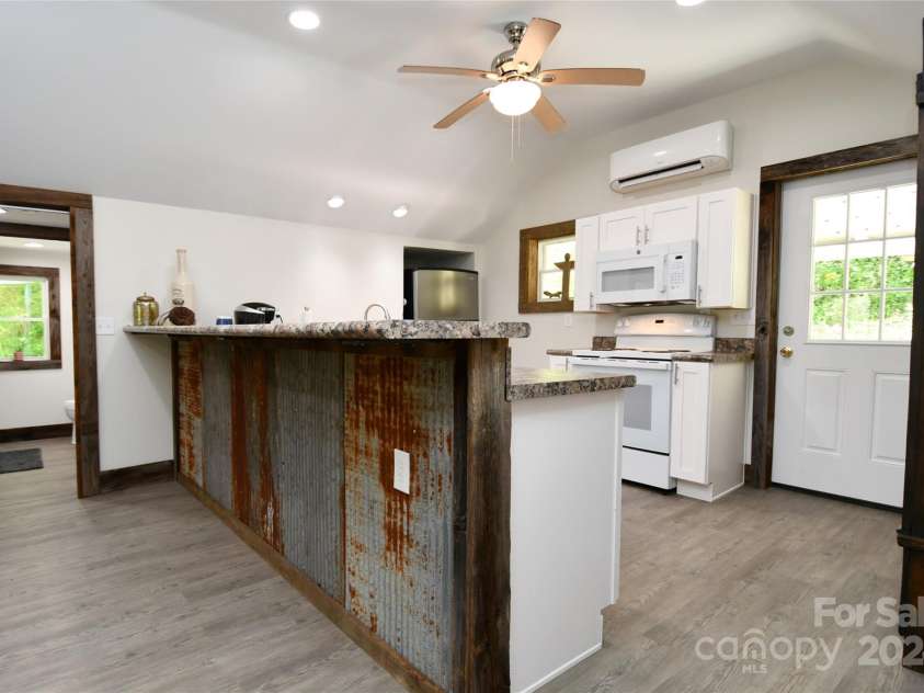 2180 Pigeon Roost Road, Green Mountain, NC 28740.  MLS# CAR4137054, YatesRealty ID 1587. The kitchen is separated from the living room by a breakfast bar accented with repurposed barn roofing