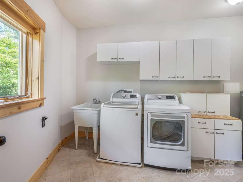 15 Sassy Lane, Asheville, NC 28805.  MLS# CAR4248835, YatesRealty ID 16032. Large laundry room with washer, dryer, sink and cabinet storage. Large window fills the room with natural sunlight