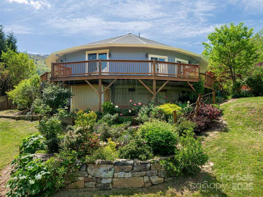 15 Sassy Lane, Asheville, NC 28805.  MLS# CAR4248835, YatesRealty ID 16032. Stone wall from the back of the house providing garden texture for the many flowering plants
