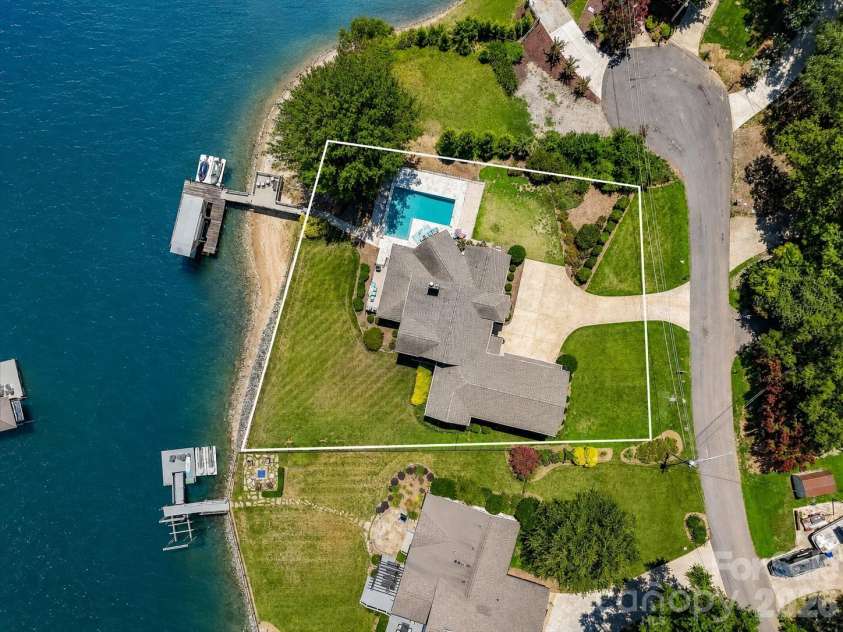 18014 Whispering Oaks Drive, Cornelius, NC 28031.  MLS# CAR4356897, YatesRealty ID 16097. Aerial view with property lines clearly illustrates the expansive waterfront homesite, private dock, pool, and generous outdoor living spaces. (Virtually enhanced lake levels)