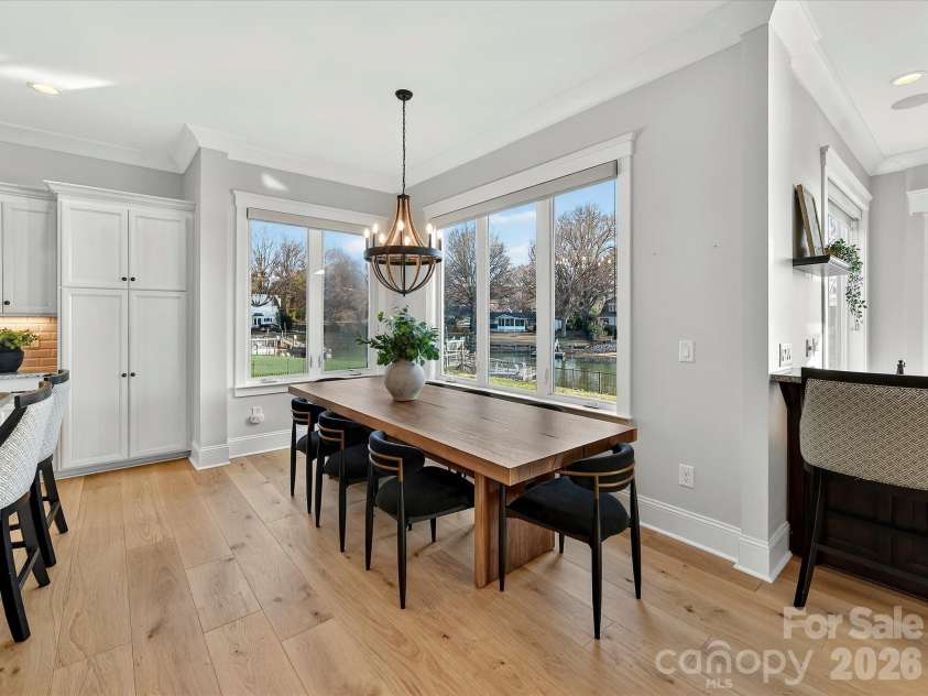 18014 Whispering Oaks Drive, Cornelius, NC 28031.  MLS# CAR4356897, YatesRealty ID 16097. Bright dining area framed by expansive windows showcases beautiful waterfront views, creating the perfect setting for everyday meals and memorable gatherings.