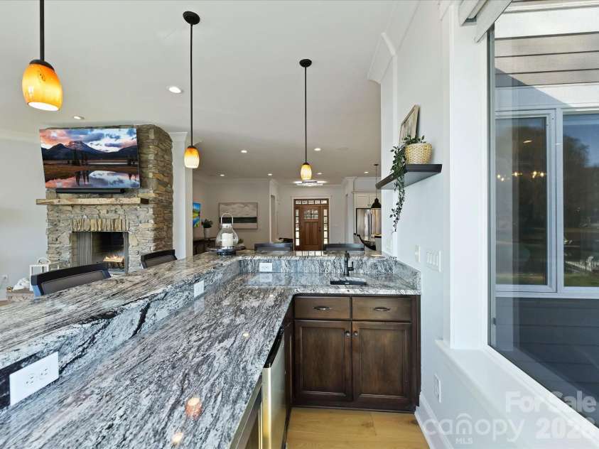 18014 Whispering Oaks Drive, Cornelius, NC 28031.  MLS# CAR4356897, YatesRealty ID 16097. Convenient main-level wet bar with granite countertops, sink, beverage refrigerator, and serving space enhances entertaining while overlooking the open living areas and Lake Norman views.