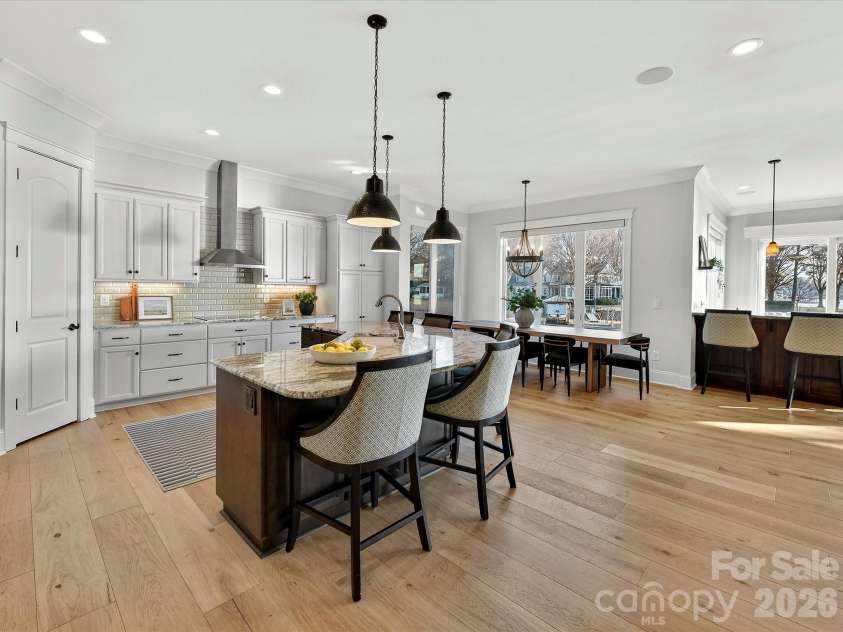 18014 Whispering Oaks Drive, Cornelius, NC 28031.  MLS# CAR4356897, YatesRealty ID 16097. Gourmet chef's kitchen features an oversized quartz island with seating, custom cabinetry, stainless steel appliances, subway tile backsplash, and seamless flow into the dining and living areas, making it ideal
