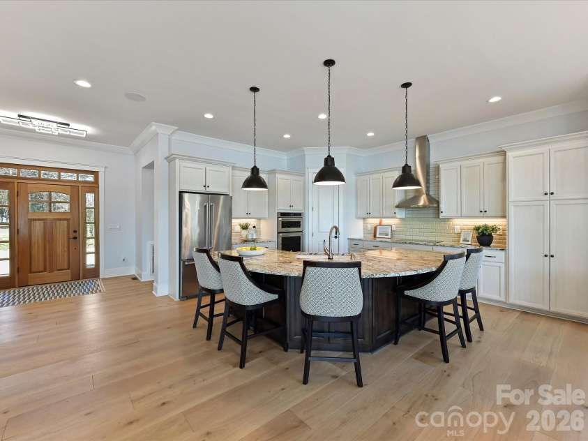 18014 Whispering Oaks Drive, Cornelius, NC 28031.  MLS# CAR4356897, YatesRealty ID 16097. Gourmet chef's kitchen features an oversized quartz island with seating, custom cabinetry, stainless steel appliances, subway tile backsplash, and seamless flow into the dining and living areas, making it ideal
