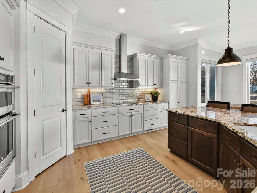 18014 Whispering Oaks Drive, Cornelius, NC 28031.  MLS# CAR4356897, YatesRealty ID 16097. Gourmet chef's kitchen features an oversized quartz island with seating, custom cabinetry, stainless steel appliances, subway tile backsplash, and seamless flow into the dining and living areas, making it ideal
