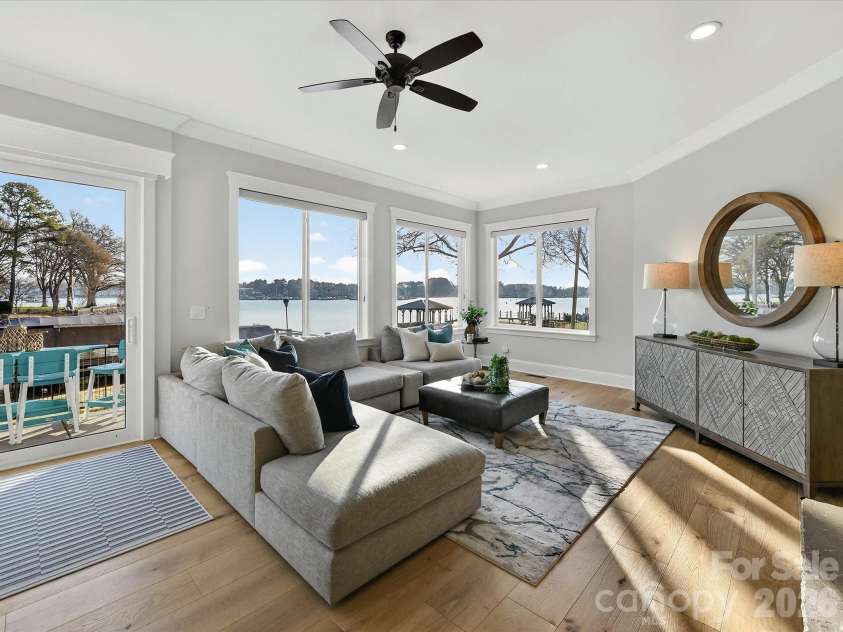 18014 Whispering Oaks Drive, Cornelius, NC 28031.  MLS# CAR4356897, YatesRealty ID 16097. Inviting Great Room showcases a striking floor-to-ceiling stone fireplace, expansive windows with stunning Lake Norman views, and seamless access to the outdoor living spaces.